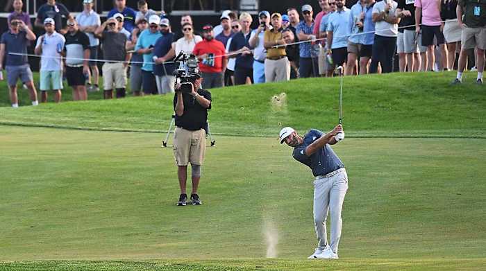 Dustin Johnson is pictured hitting a shot in front of a TV camera at the 2022 LIV Golf Invitational Chicago.